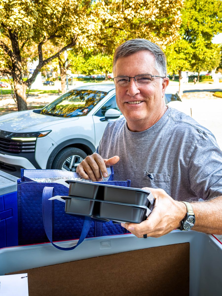 A VNA volunteer loading Meals on Wheels coolers into a car